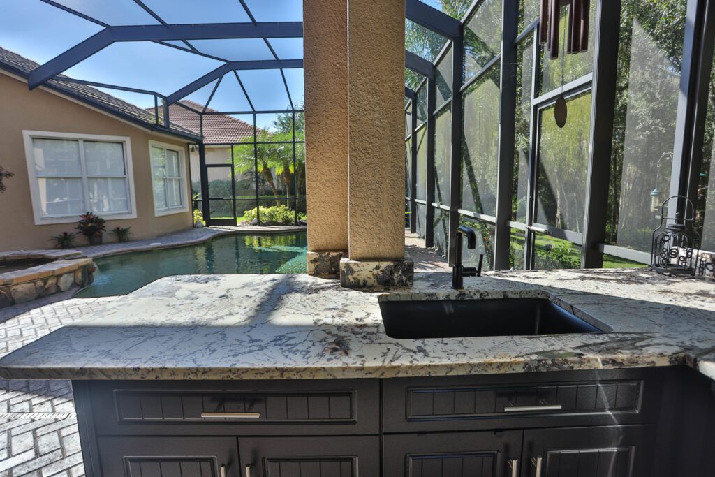 light granite counter tops with sink and black cabinetry in outdoor kitchen in Florida