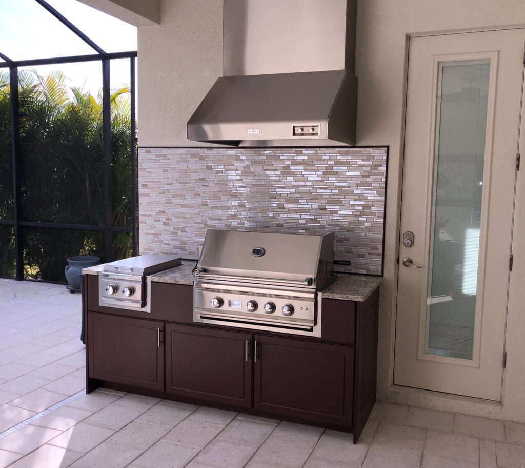 brown outdoor kitchen with vent hood, tile backsplash, and summerset grill 