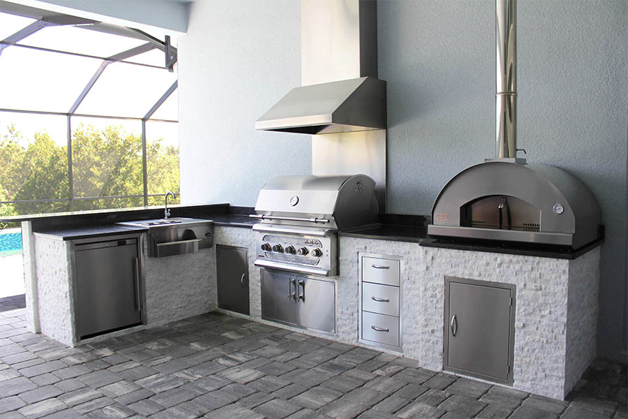 Custom outdoor L shaped kitchen with vent hood and pizza oven and natural stone