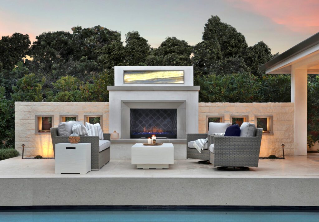 neutral patio furniture next to a fire and a sunset in the background 