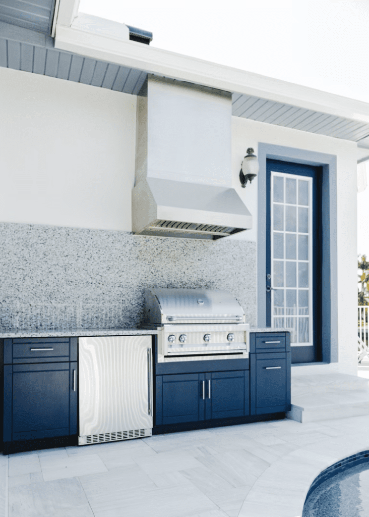 Grill with hood and fridge with blue cabinets by pool