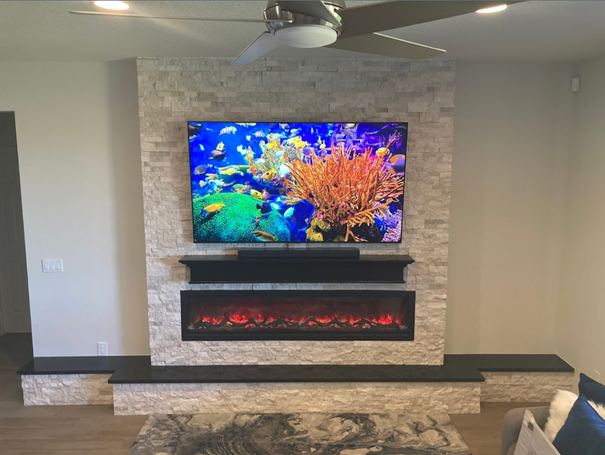 TV and fireplace installed in indoor rock wall feature