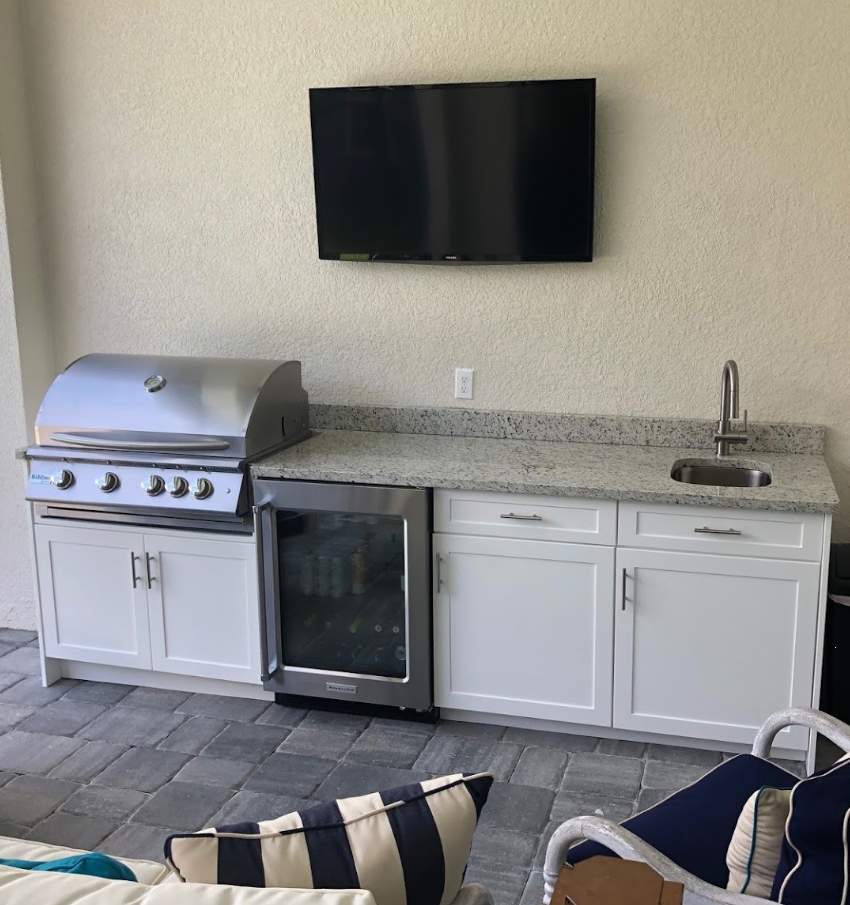 Outdoor kitchen with white cabinet by TV