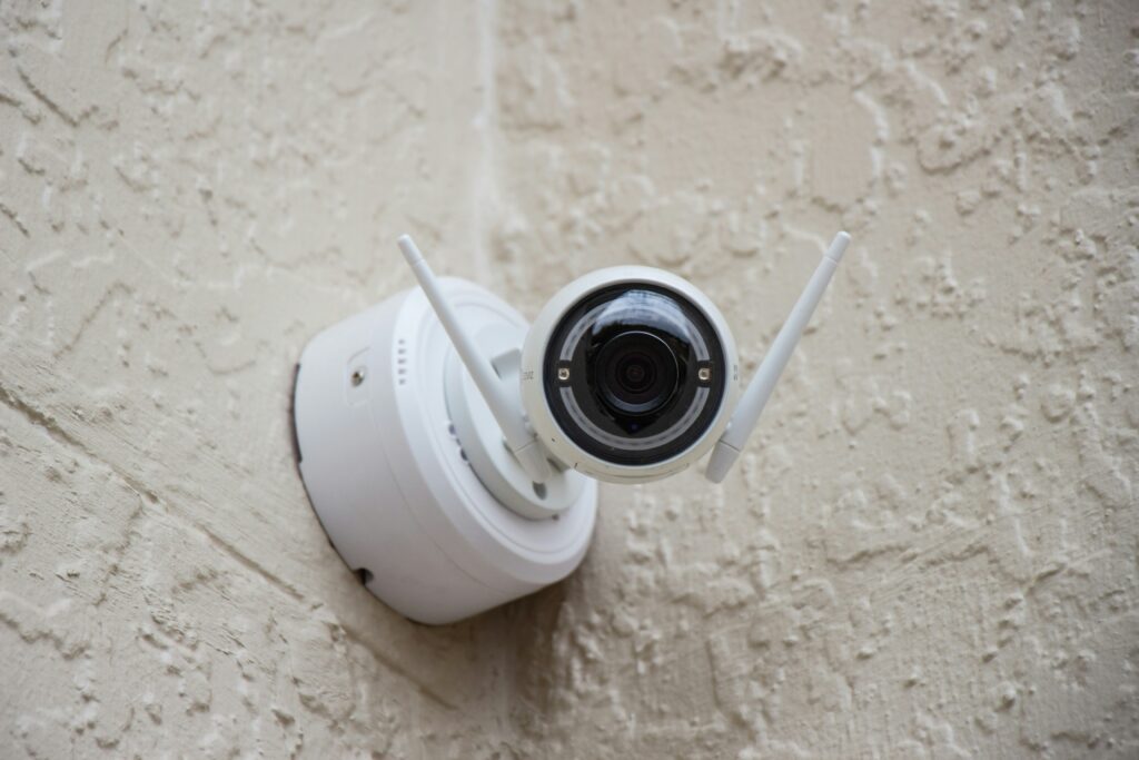 white security camera on wall outside of house 