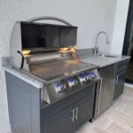 Outdoor kitchen with grill, fridge, and sink