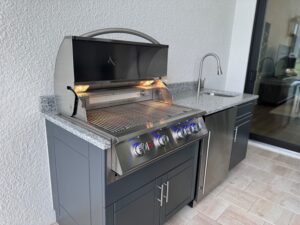 Outdoor kitchen with grill, fridge, and gray cabinets