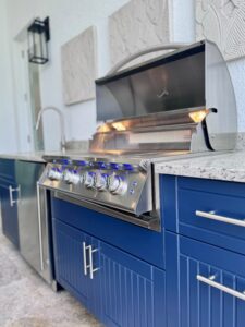 Outdoor kitchen with grill, fridge, and navy blue cabinets