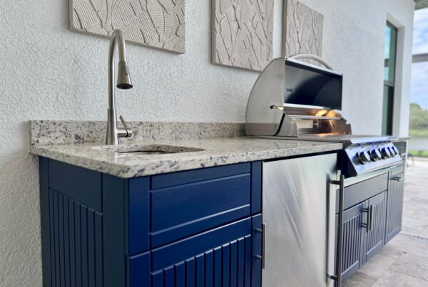 Outdoor kitchen with grill, fridge, and navy blue cabinets