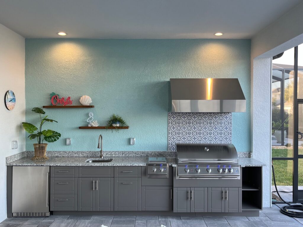 coastal inspired outdoor kitchen with gray cabinets and backsplash 